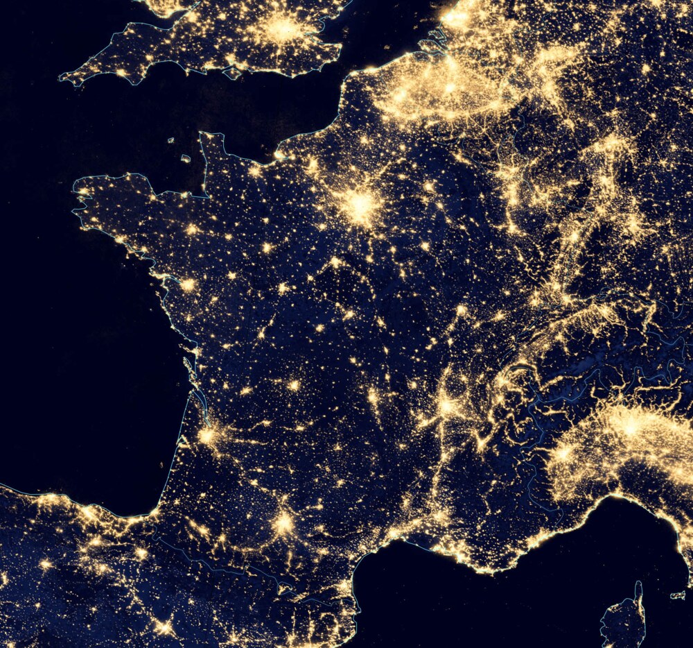 France seen at night from orbit, with cities forming a network of lit nodes and filaments
